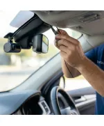 لقطة مقربة ملتقطة من داخل مركبة تُظهر يد فني في الرياض وهي تقوم بعناية بدس سلك أسود رفيع لكاميرا لوحة القيادة (داش كام) المثبتة حديثًا داخل تنجيد سقف السيارة، بجوار مرآة الرؤية الخلفية.