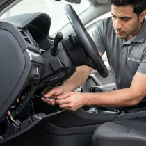 فني يقوم بتركيب جهاز تتبع (GPS) مخفي باحترافية داخل لوحة القيادة (الطبلون) للسيارة.